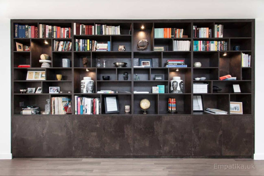 Full view of dark coloured floor to ceiling display unit with asymmetrical shelves and bottom storage closets