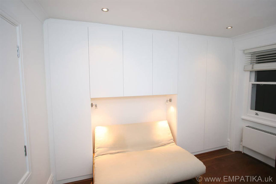 Floor to ceiling wardrobes with slim doors and a sofa bed with custom lighting in the alcove