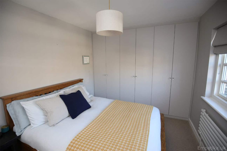 Full view of bedroom with built in eco-fitted Formaldehyde-free wardrobes painted White with round crystal handles