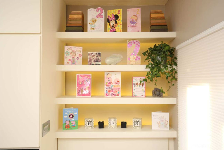 Closer view of custom White painted fitted shelves with yellow backlights