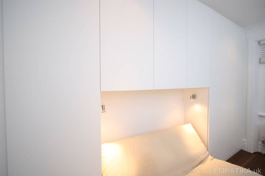 Alcove wardrobes with custom lighting for a sofa bed and overhead cupboards all painted White