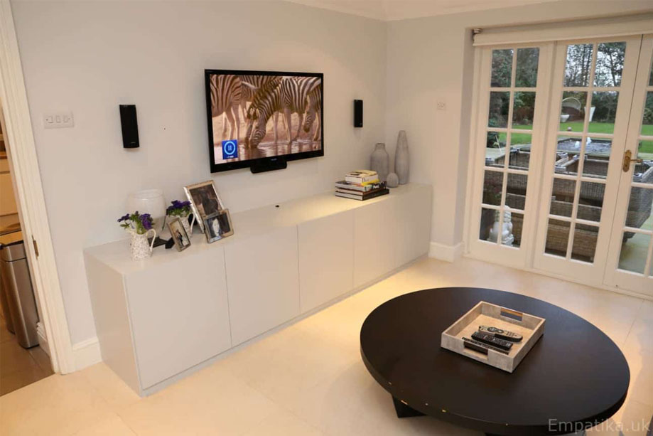 White painted built in media unit with wall mounted TV and 2 speakers on either side
