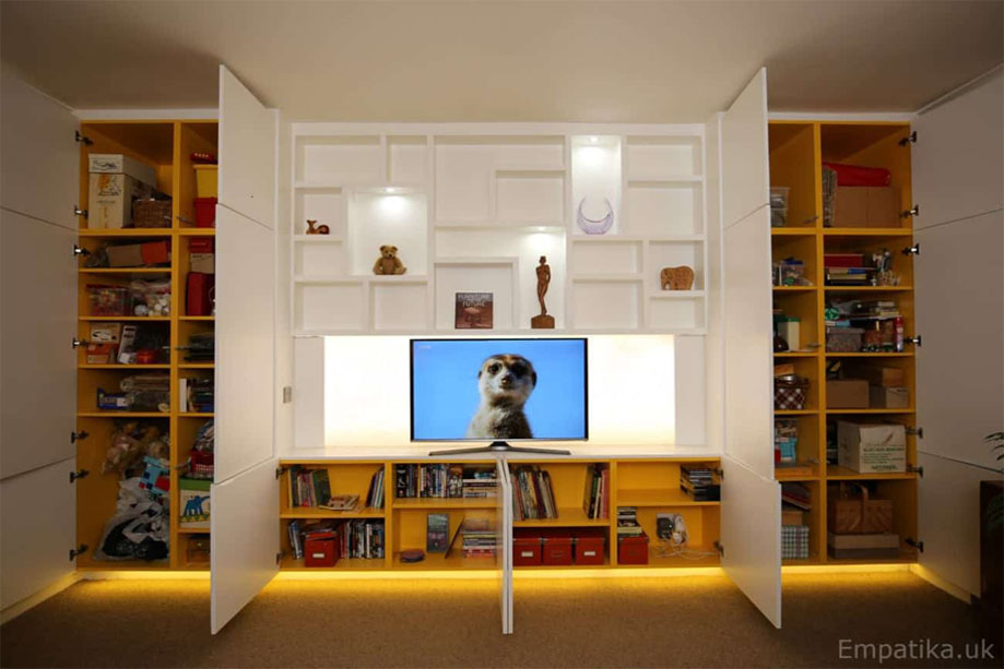 Full view of large fitted storage furniture with LED panel TV media stand in the middle and multi-door closets with spacious interior shelves on the side and bottom