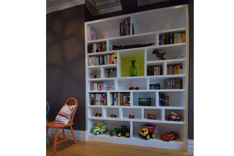 White custom made bookshelves with ornaments, books and childrens toys on it