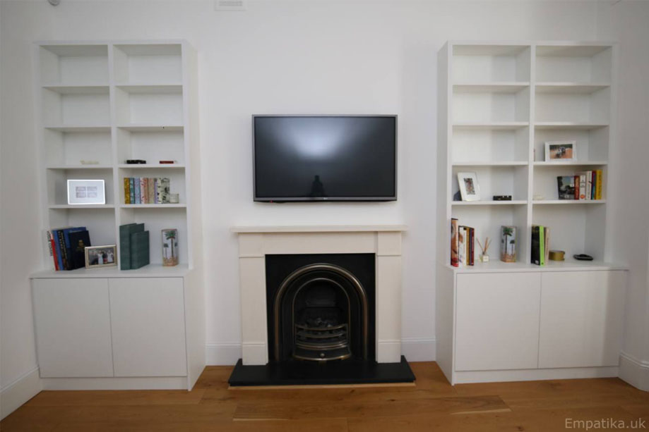 Identical alcove cupboards with shelves painted White with a fireplace and wall-mounted TV in between