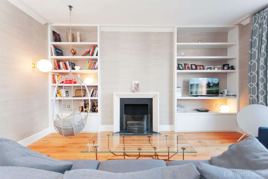 2 floor to ceiling White painted custom media shelves with a fireplace in the alcove