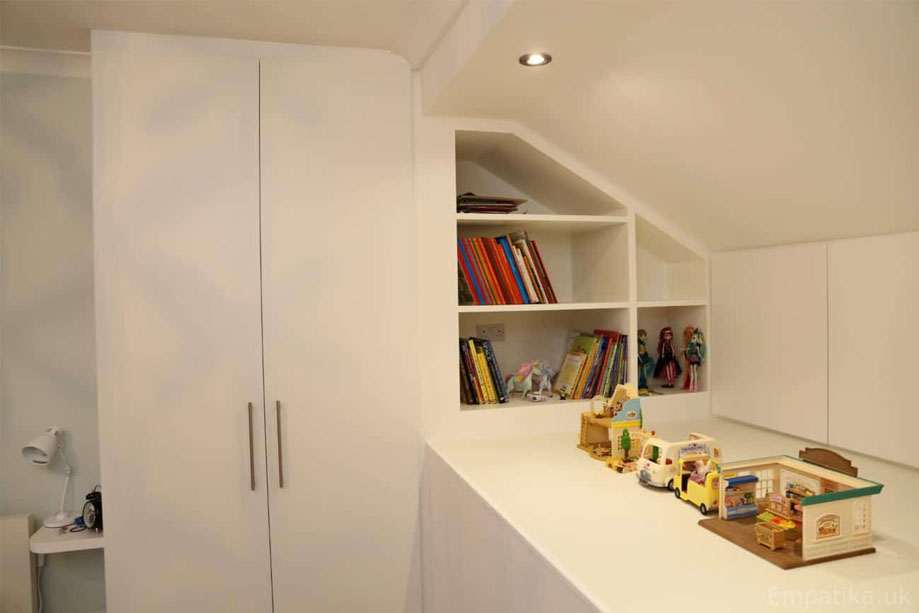 Children's bedroom with custom floor to ceiling alcove wardrobes, floating bedside shelves, and angled ceiling small bookcase