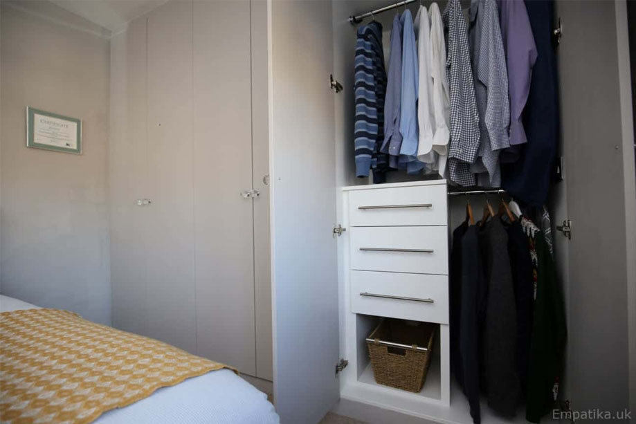 Interiors of White painted eco-ffited bedroom wardrobes with clothes rail, drawers, and custom shelving
