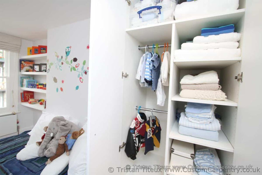 Fitted floor to ceiling children's room wardrobe painted White with double clothes racks and several storage shelves inside