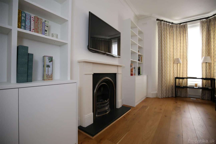 Side view of bespoke White painted identical alcove cupboards with a wall mounted TV and fireplace in between