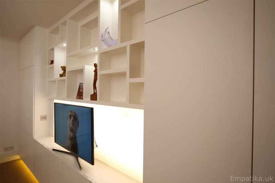 Tall cupboards with LED light TV unit and asymmetrical shelving in the alcove all painted White