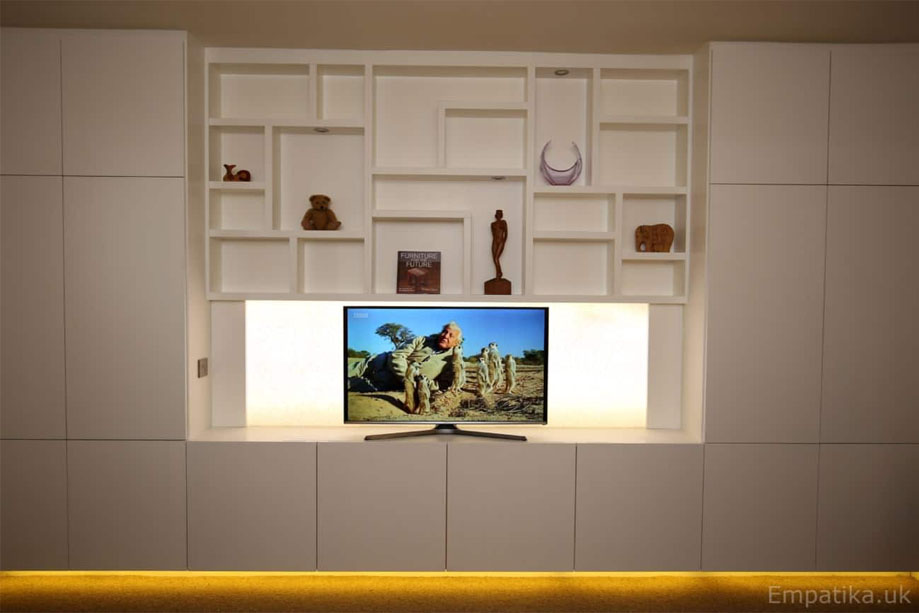 Fitted wall to wall display unit painted White with asymmetrical open shelving, surrounding closets, and furniture underglow