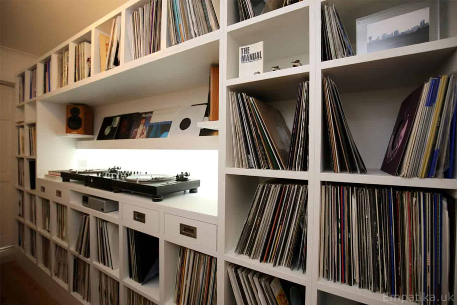 Side view of custom fitted storage unit painted White with many square record shelves and a LED panel horizontal shelf in the center