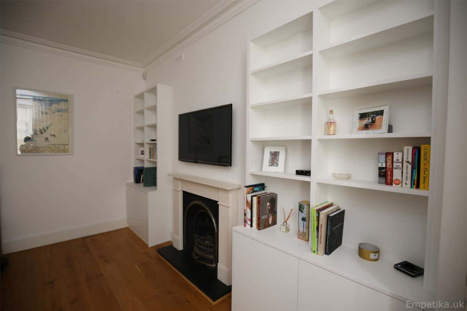 Right side view of 2 White painted identical alcove cupboards with shelves with a fireplace in between