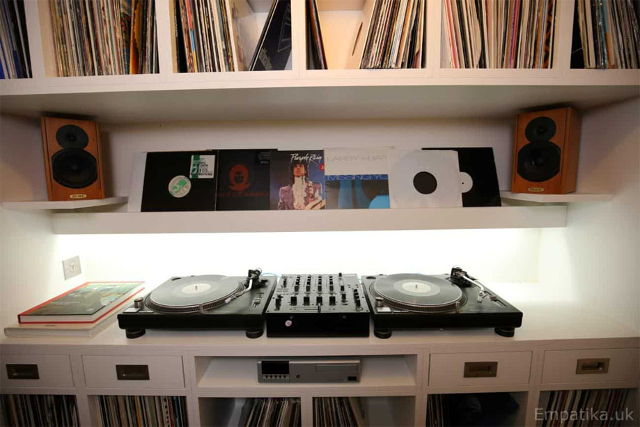Wall to wall fitted media unit painted White with square record shelves surrounding a turntable storage with LED backlight
