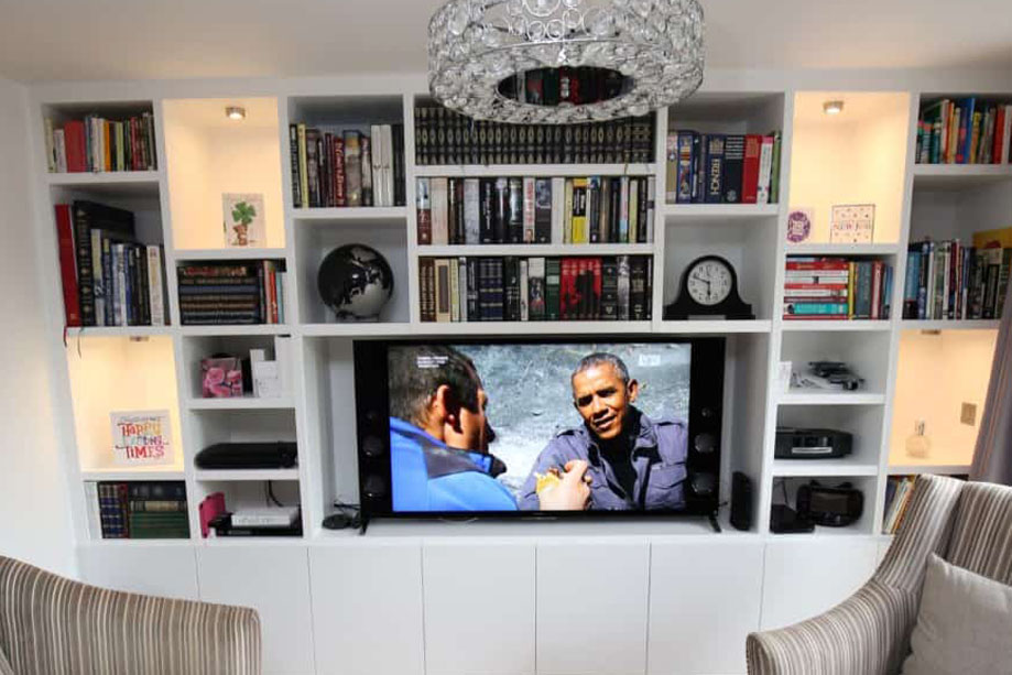 White painted media unit with built in library bookcase above with 4 random LED lights shelves