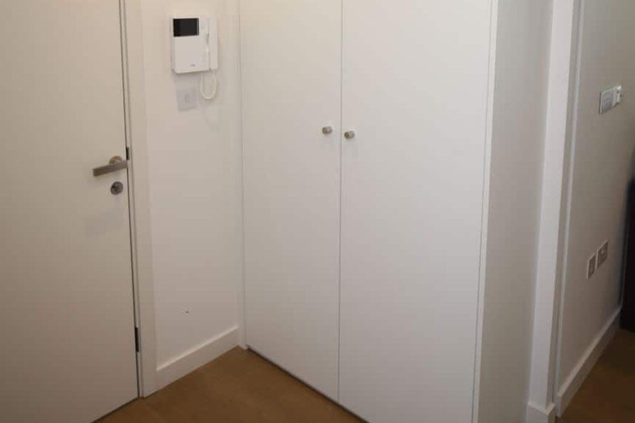 Side view of White painted built in floor to ceiling fitted storage cupboard in the hallway