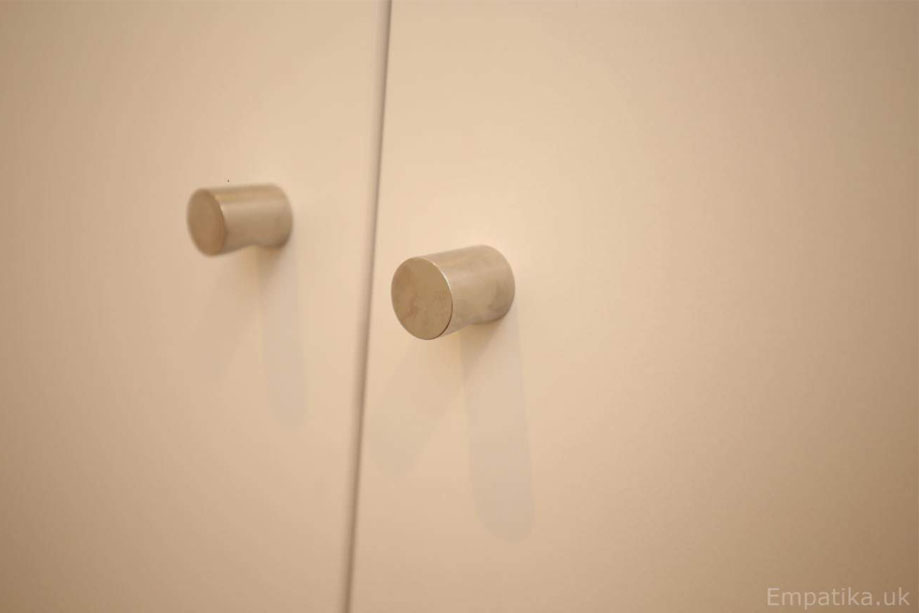 Close up view of White painted cupboard small steel door handles