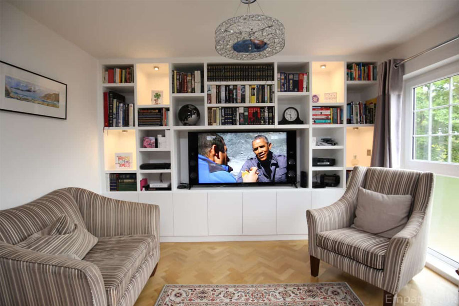 Wall to wall fitted large TV media unit with several bottom closets and bookcase above