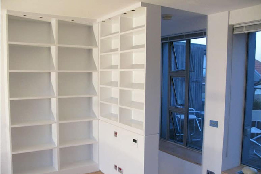 White painted library bookcase with top shelf LED lights built on two corner walls
