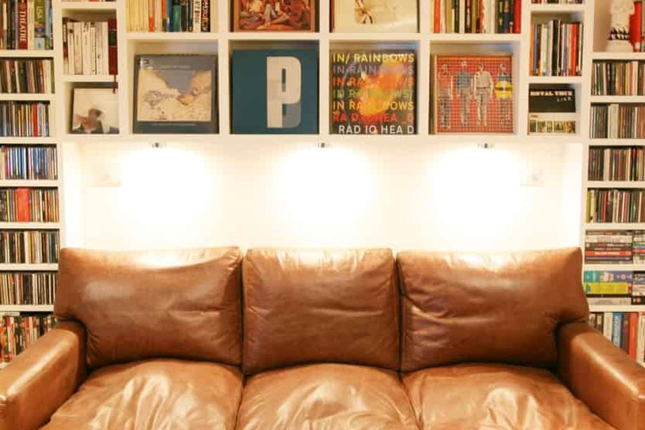 White painted library bookcase with a sofa in the center and overhead lights and shelves