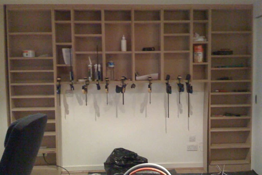 Wide prefinished library bookcase being installed on a bare wall