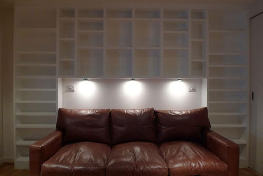 White painted built-in library bookcase with sleeper sofa and LED lights in the center