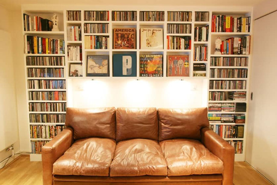 Full view of built in library bookcase with a combination of vertical shelves and square record shelves all painted White