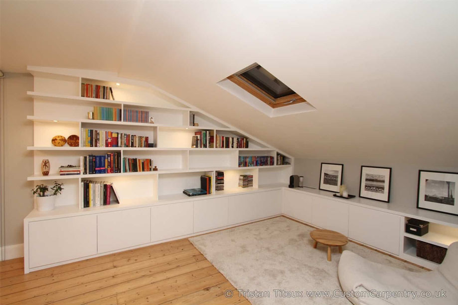 Full view of custom fitted library bookcase with asymmetrical shelves and bottom closets built on two walls