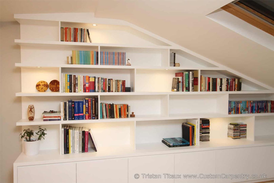 Front view of ceiling high bookcase painted White with spacious asymmetrical shelves and accent LED lights