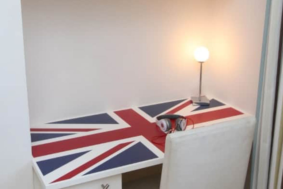 Corner fitted Union Jack desk with drawers and shelves above all painted White in children's bedroom