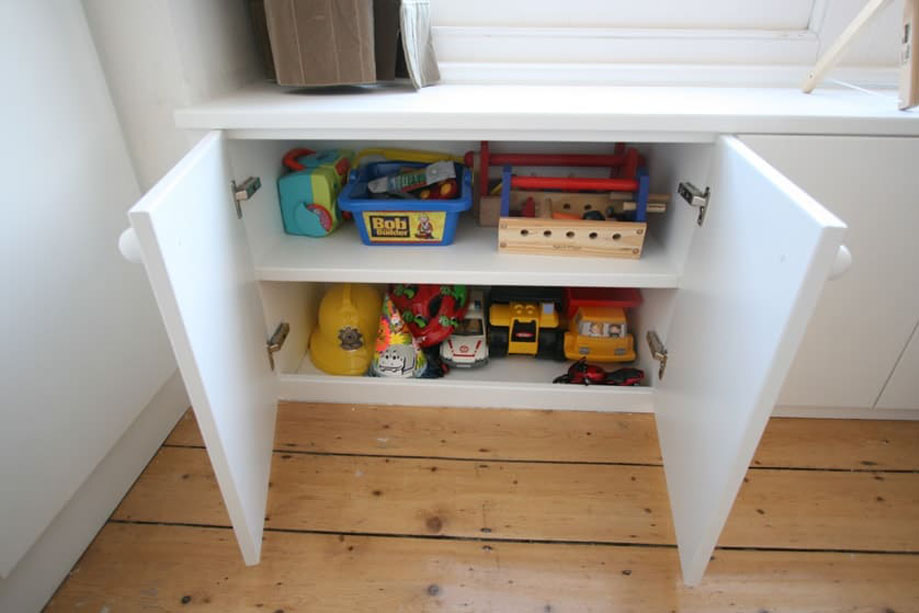 Interiors of custom low cupboards in children's bedroom with spacious storage shelving painted White