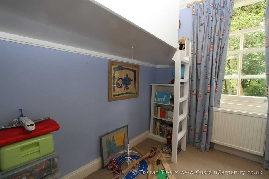 Custom White painted children's room loft bed with a play area and small bookcase below