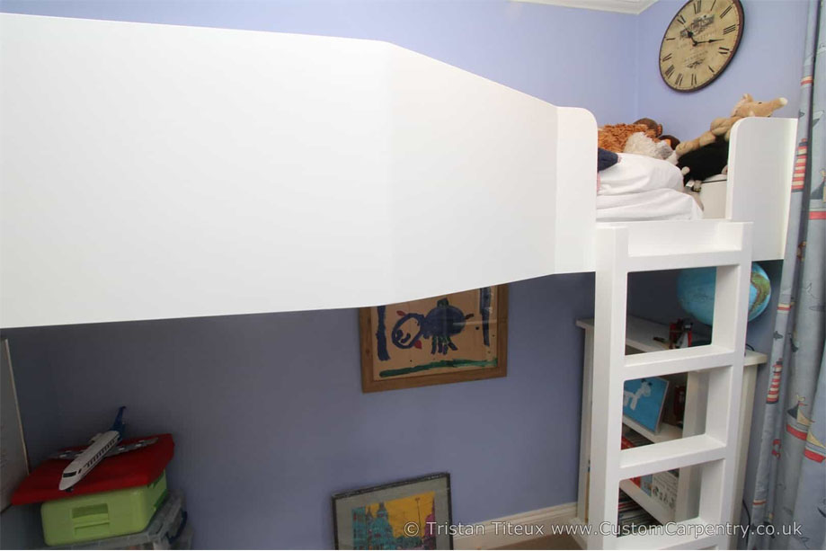 Fitted White painted loft bed with play area and bookcase underneath inside a chldren's bedroom