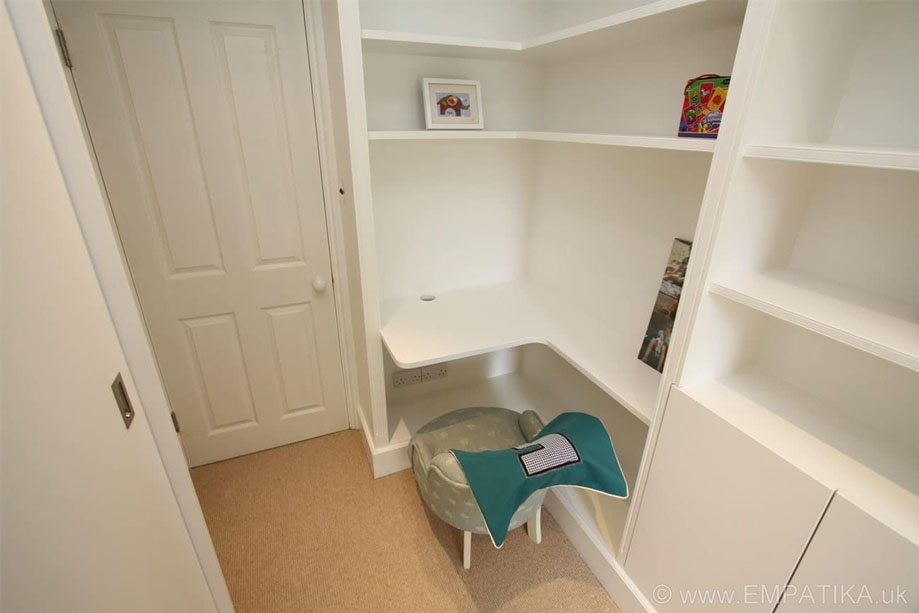 Built in L-shaped desk with shelves and cupboards by the door of children's room