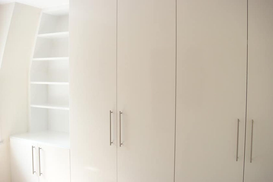 3 sets floor to ceiling wardobes painted White with an angled ceiling open shelving on the corner
