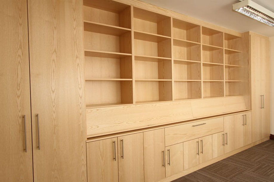Custom wall to wall veneered cupboards with 2 floor to ceiling closet doors on each side, center open shelving, and bottom cabinets and a drawer all with steel handles