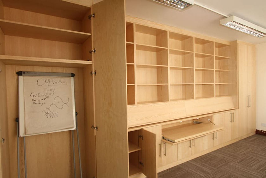 Wall to wall fitted cupboards in light wooden finish with ceiling high open shelving and closets on either side and on the bottom