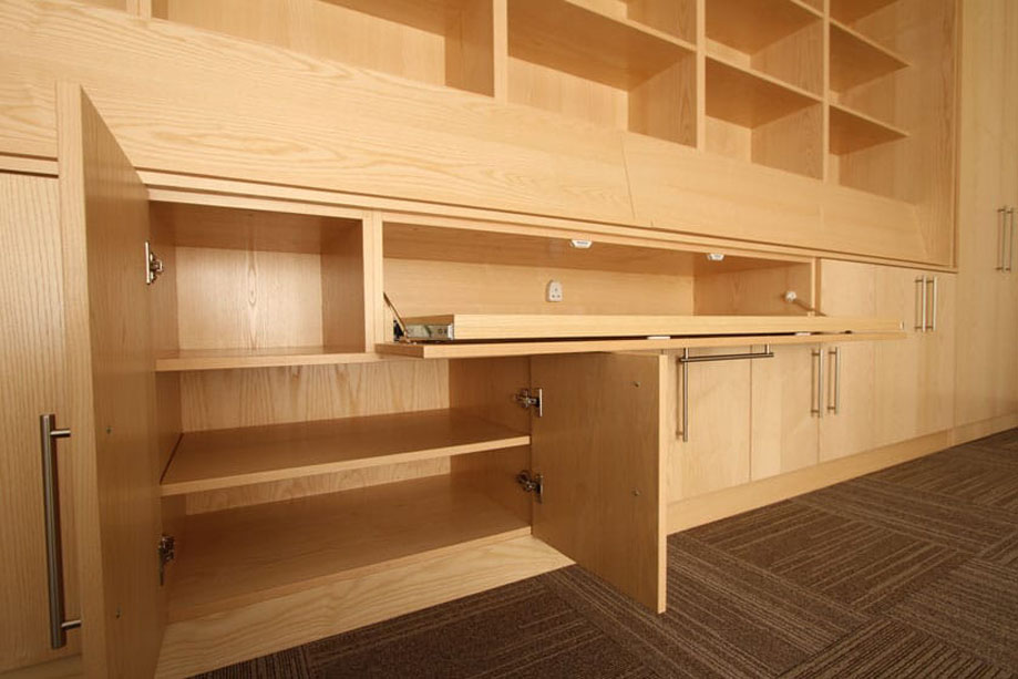 Interiors of built in wall cupboards with spacious shelving and pull down media cabinet with electrical outlet