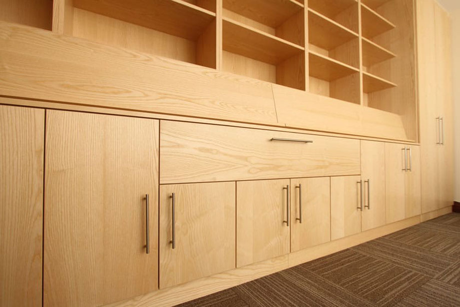 View from the side of bottom cupboards and pull down media cabinet with steel bar handles