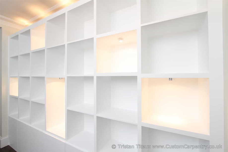 Closer view of White painted luxurious library bookcase with random LED light shelves and top ambient lighting