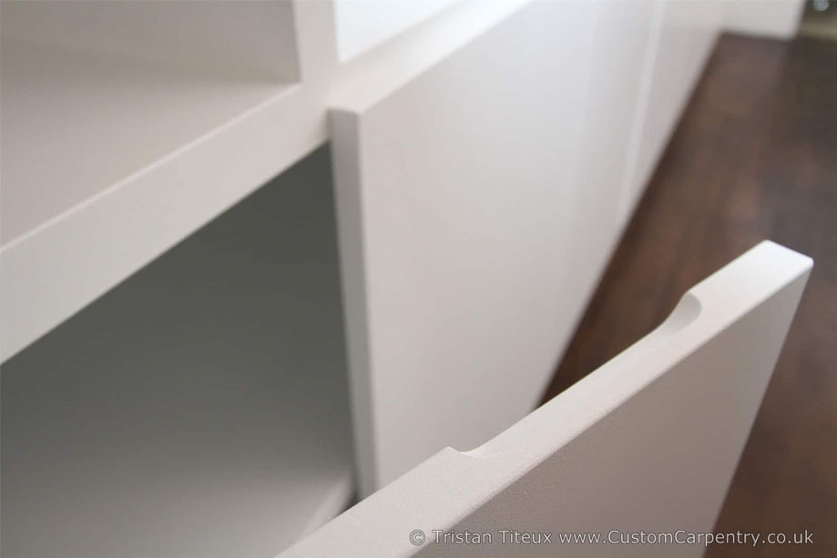 Closer look at White painted display unit with bottom closets with edge pocket doors for easy opening