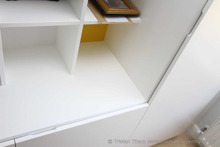 Fitted White painted home cupboards with recessed open shelving in the center