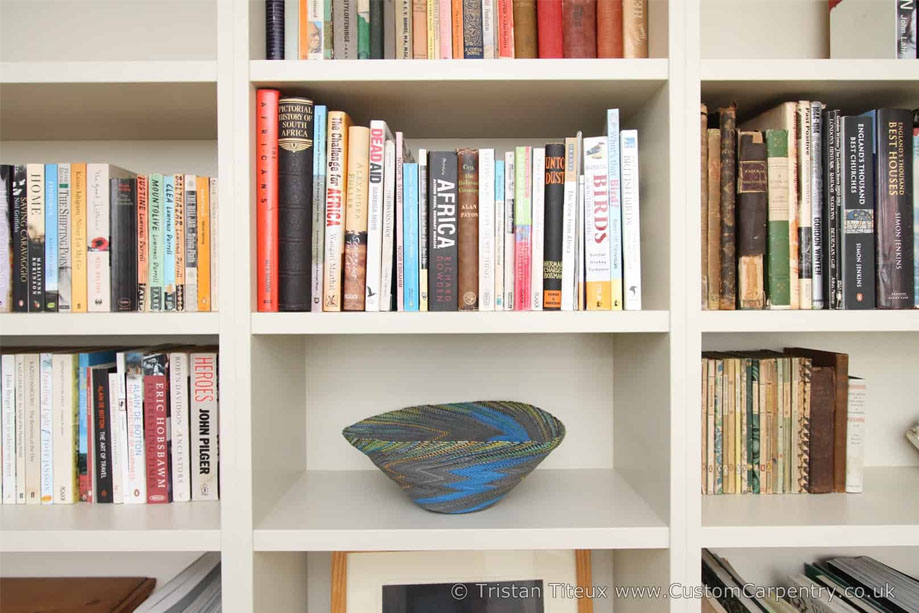 Close up view of fitted library bookcase with symmetrical handpainted shelves