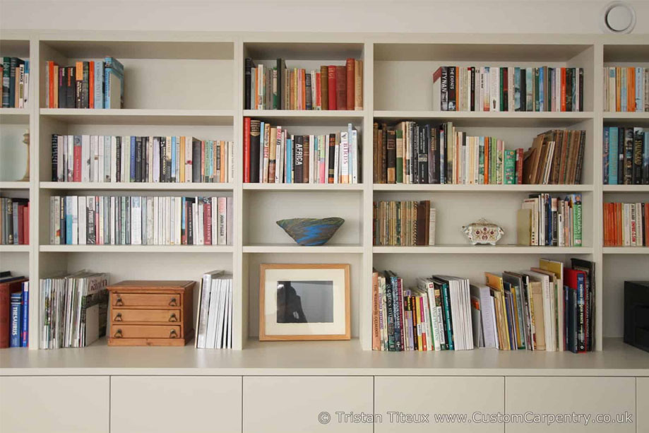 Front view of bespoke library bookcase with alternating wide and narrow shelving and bottom closets