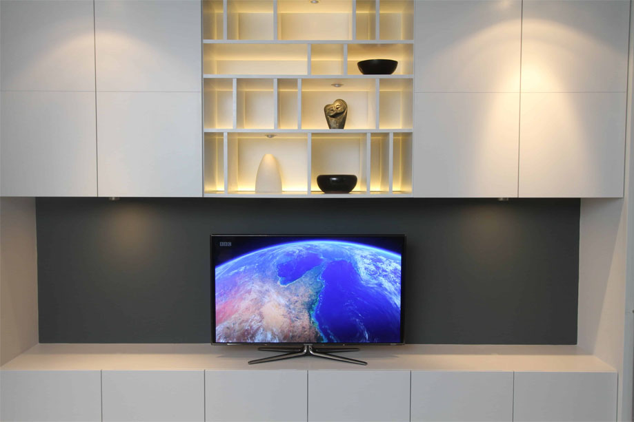Custom built TV media unit with cupboards and LED light open shelving above all painted White