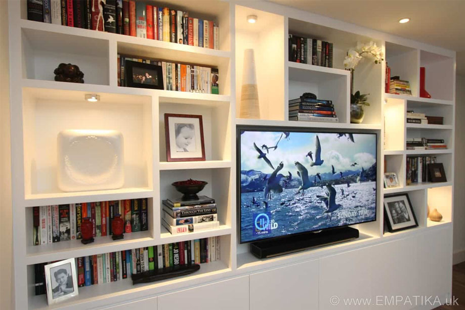 Large ceiling high TV media unit with asymmetrical surrounding shelves and bottom closets