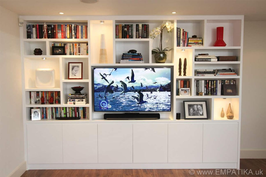 Large living room media unit painted White with asymmetrical shelves surrounding a flatscreen TV and 6-door bottom closets