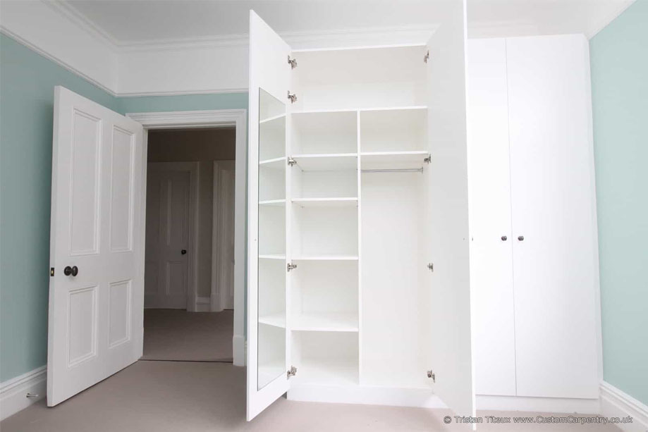 Large eco fitted bedroom wardrobes painted White with shelves, clothes rack, and a door-mounted mirror inside