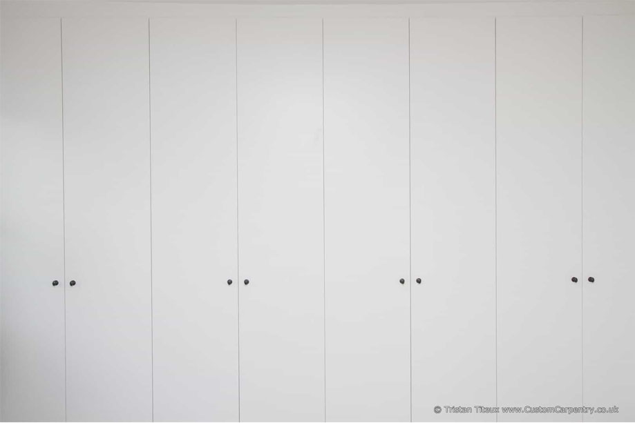 Front view of 8-door White painted fitted wardrobes with small round handles